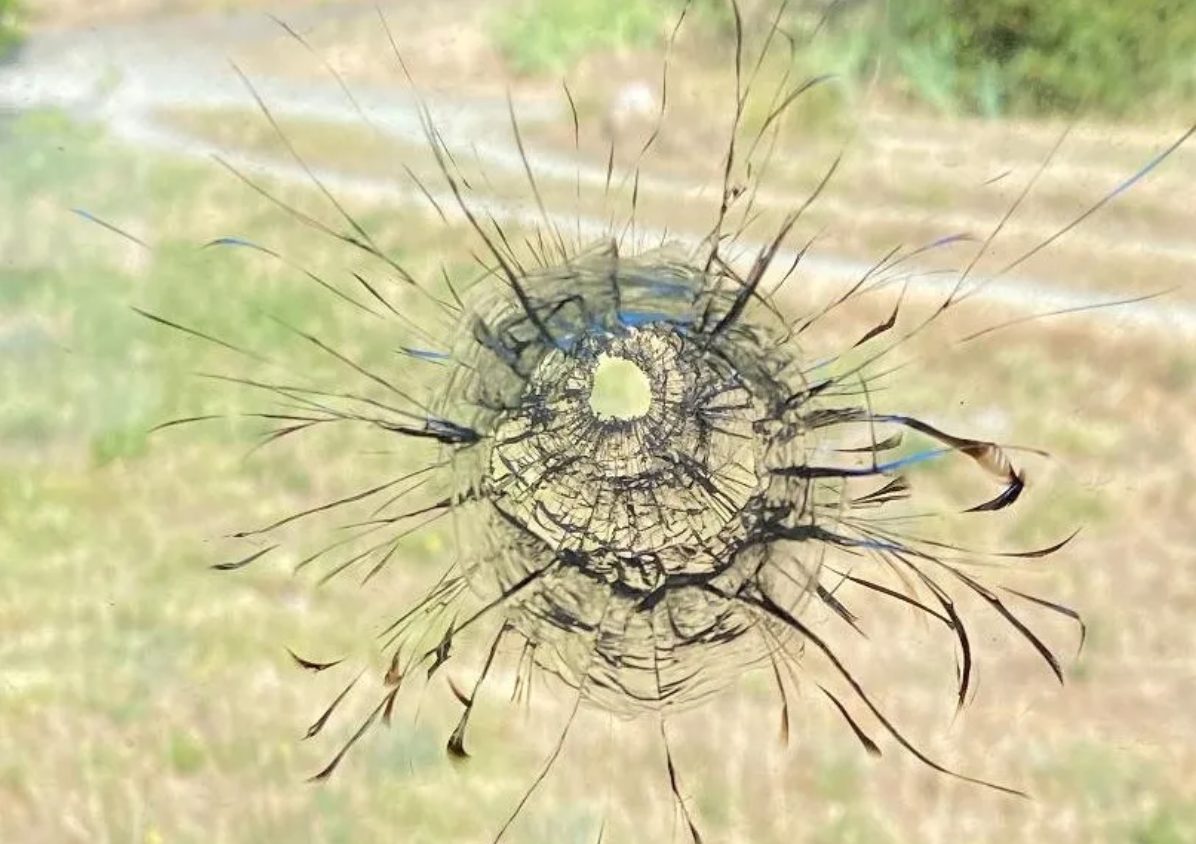 image of window with a bullet hole and cracked glass